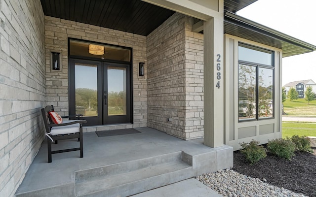 doorway to property with a porch, french doors, and brick siding