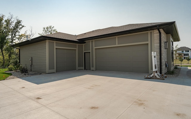 exterior space featuring driveway, roof with shingles, and an attached garage