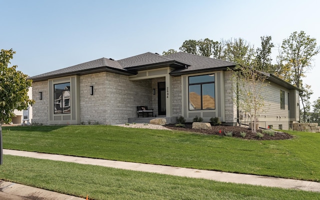 view of front facade with stone siding, a shingled roof, and a front yard