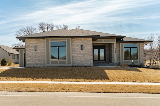 prairie-style house with french doors, stone siding, and roof with shingles