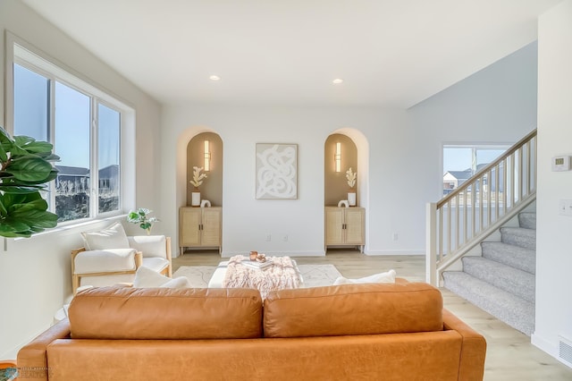 unfurnished living room featuring recessed lighting, light wood-style floors, a healthy amount of sunlight, and stairs