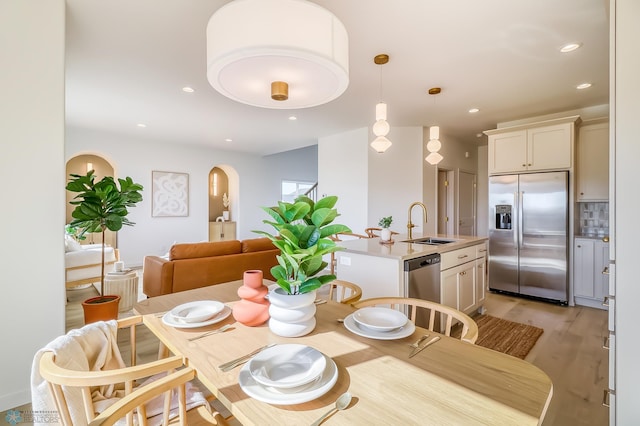 dining space with recessed lighting, light wood-type flooring, and arched walkways