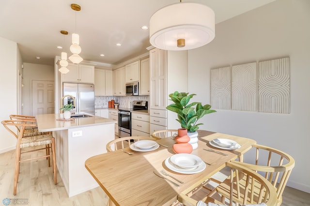 dining room with light wood finished floors, recessed lighting, and baseboards