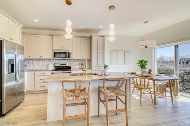 kitchen featuring a sink, decorative light fixtures, tasteful backsplash, appliances with stainless steel finishes, and light countertops