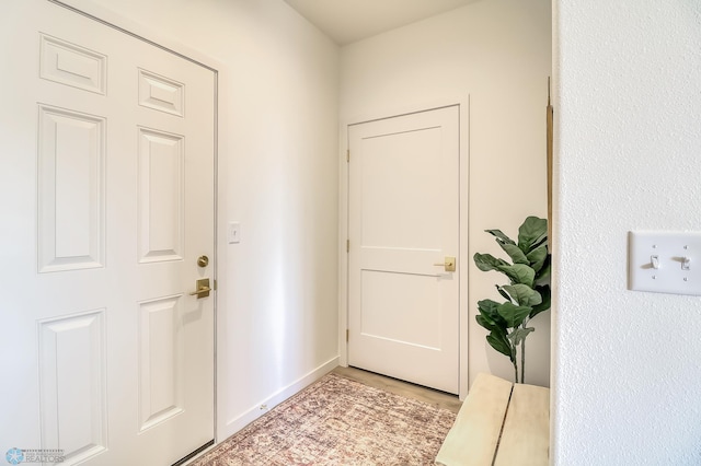 doorway with light wood-style floors and baseboards