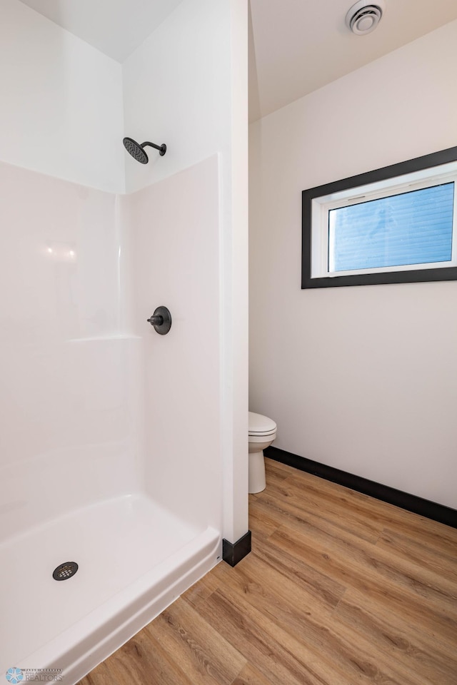 full bath featuring visible vents, toilet, wood finished floors, baseboards, and walk in shower