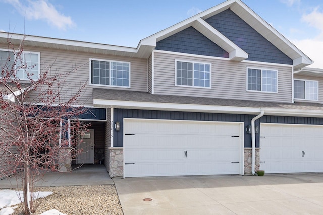 view of property featuring driveway, a garage, and stone siding