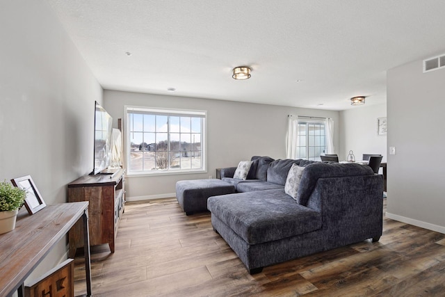 living area with dark wood finished floors, baseboards, visible vents, and a textured ceiling