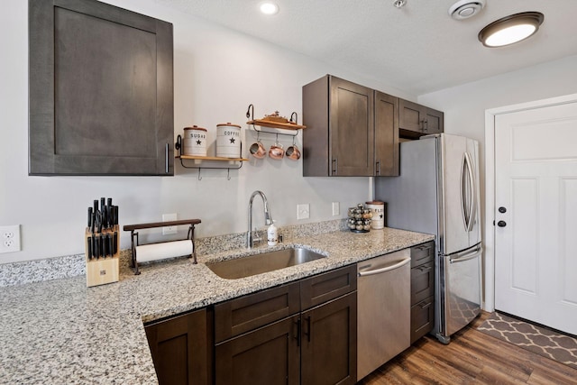 kitchen with a sink, stainless steel appliances, dark brown cabinets, and dark wood-style flooring