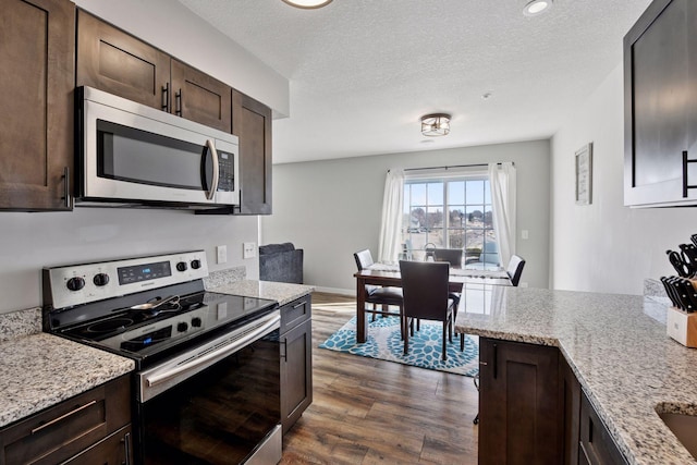 kitchen featuring light stone counters, a textured ceiling, dark wood-style floors, stainless steel appliances, and dark brown cabinetry