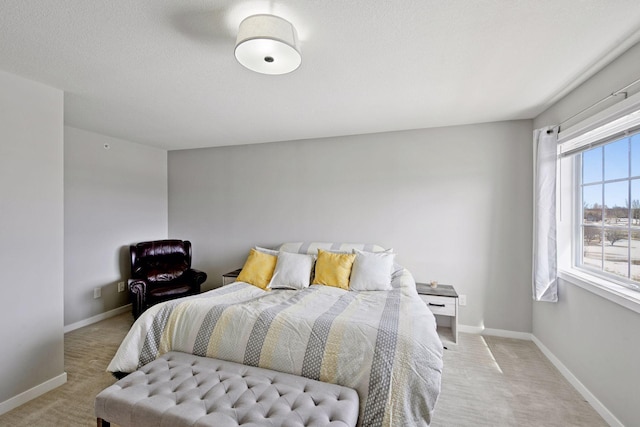 bedroom with light colored carpet, a textured ceiling, and baseboards