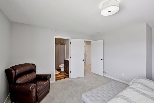 bedroom featuring light carpet, visible vents, ensuite bath, and baseboards