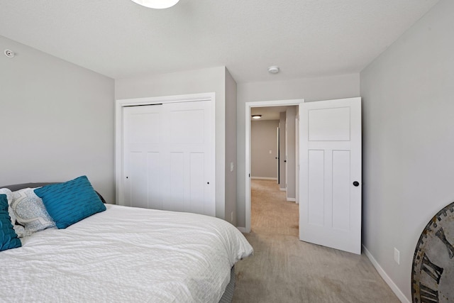 bedroom with a closet, light colored carpet, and baseboards