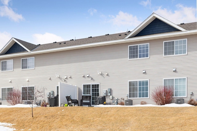 rear view of property with central air condition unit and a yard