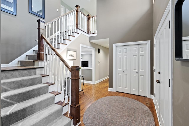 entrance foyer with stairway, a high ceiling, wood finished floors, and baseboards