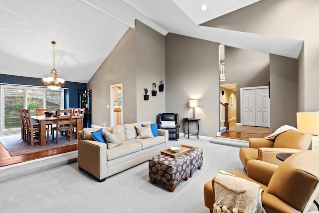 carpeted living area with baseboards, high vaulted ceiling, and an inviting chandelier