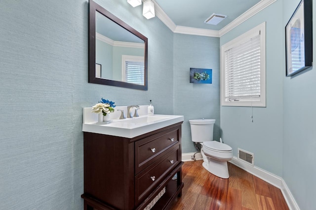 bathroom featuring wood finished floors, visible vents, baseboards, crown molding, and toilet