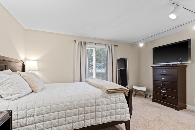 bedroom featuring rail lighting, light colored carpet, and baseboards