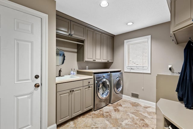 washroom with visible vents, baseboards, cabinet space, separate washer and dryer, and a sink