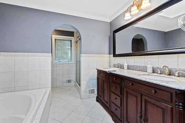 bathroom featuring visible vents, ornamental molding, a sink, tile walls, and double vanity