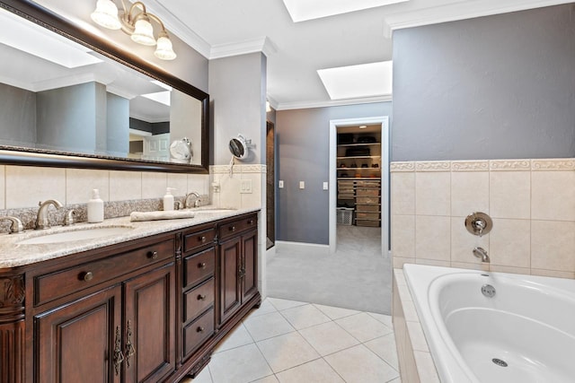 bathroom with tile patterned flooring, crown molding, a garden tub, a skylight, and a sink