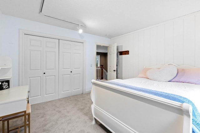 bedroom featuring a closet, light carpet, and rail lighting