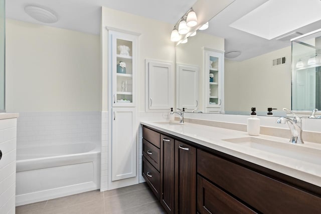 bathroom featuring tile patterned floors, a garden tub, visible vents, and a sink