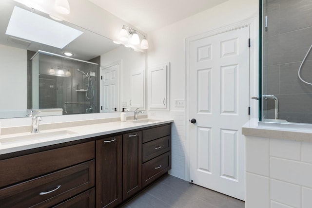 bathroom with a sink, tile walls, a stall shower, and a skylight