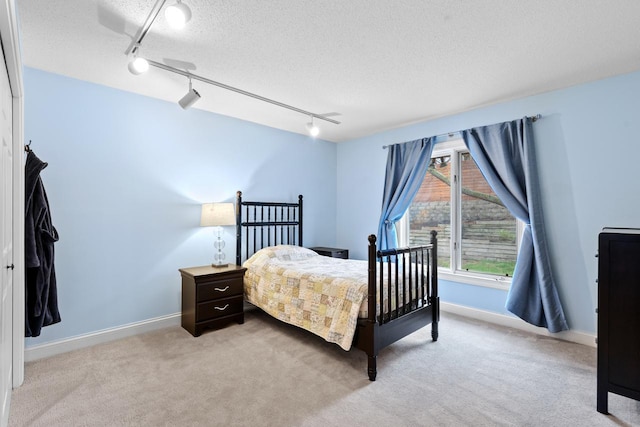 bedroom with a textured ceiling, baseboards, and light carpet