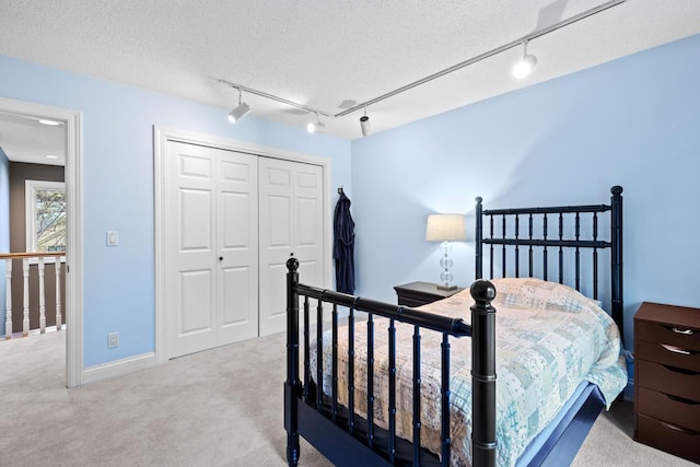 bedroom featuring a closet, baseboards, a textured ceiling, and carpet flooring