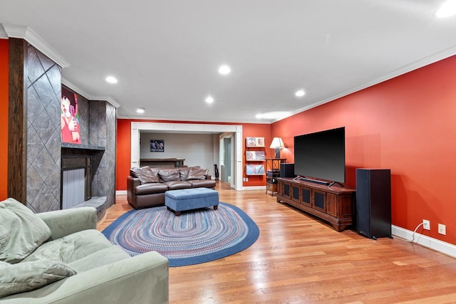 living area with recessed lighting, a large fireplace, light wood-style floors, crown molding, and baseboards