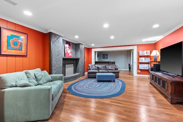 living room with recessed lighting, a premium fireplace, wood finished floors, and crown molding