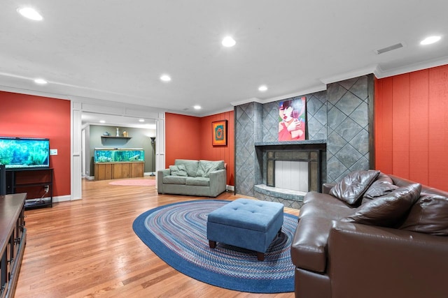 living room with baseboards, ornamental molding, recessed lighting, a tile fireplace, and wood finished floors