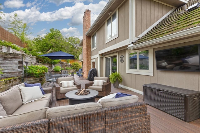 wooden terrace with an outdoor living space with a fire pit