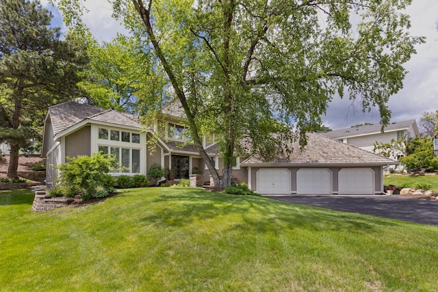 view of front of property with a front yard, an attached garage, brick siding, and aphalt driveway