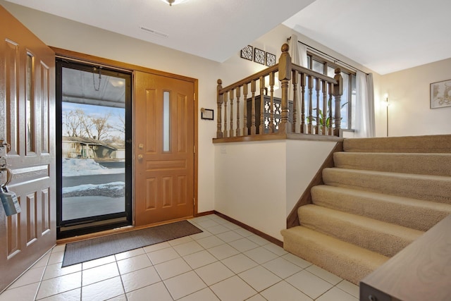 foyer entrance featuring stairs, light tile patterned flooring, and baseboards