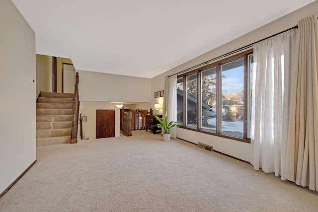 carpeted empty room with visible vents, stairs, and baseboards