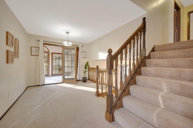 carpeted entrance foyer featuring stairway, french doors, and baseboards