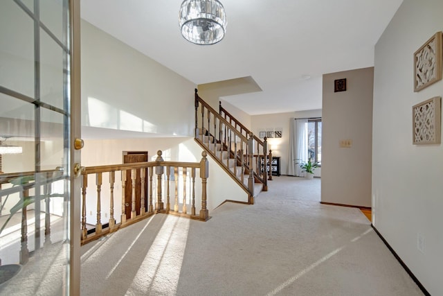 hallway with stairs, baseboards, carpet floors, and a chandelier