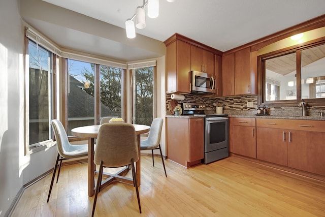 kitchen featuring a healthy amount of sunlight, tasteful backsplash, appliances with stainless steel finishes, and light wood-type flooring