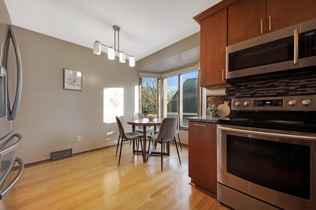 kitchen with brown cabinets, visible vents, backsplash, and stainless steel appliances