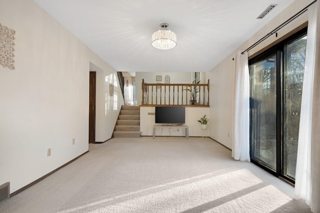 unfurnished living room with stairs, plenty of natural light, carpet, and visible vents