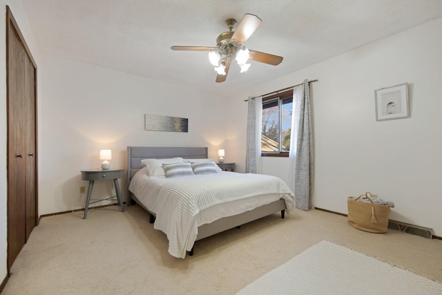 bedroom featuring a ceiling fan, visible vents, baseboards, a closet, and light colored carpet