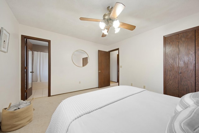 bedroom featuring a closet, light colored carpet, ensuite bath, and ceiling fan