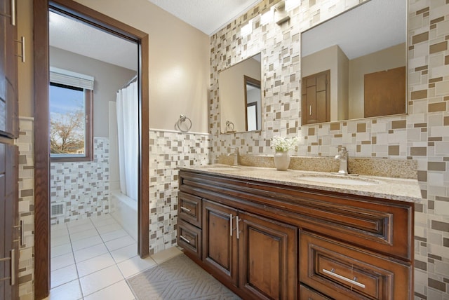 bathroom featuring visible vents, a sink, shower / tub combo, tile patterned floors, and tile walls