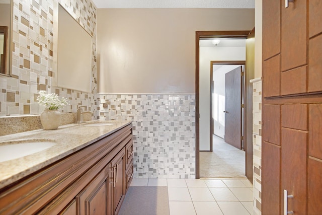 full bathroom featuring tile patterned flooring, tile walls, double vanity, and a sink