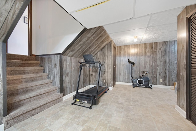 exercise room featuring baseboards and wood walls