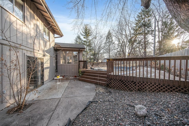 exterior space featuring a patio area, a wooden deck, and a shingled roof