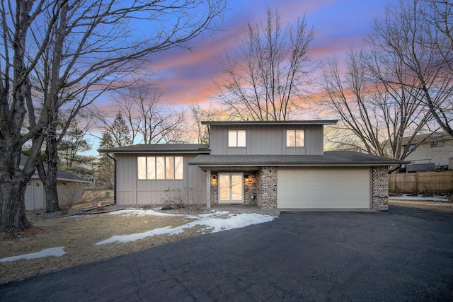 split level home with a garage, fence, brick siding, and driveway