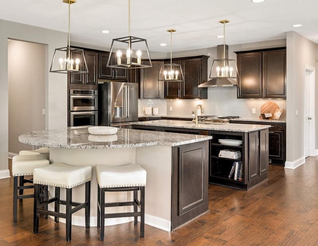 kitchen featuring an island with sink, stainless steel appliances, dark brown cabinets, tasteful backsplash, and dark wood-style flooring